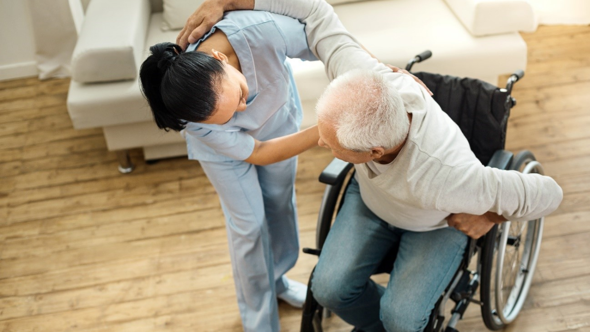 車いすの高齢男性を介助する介護職の女性